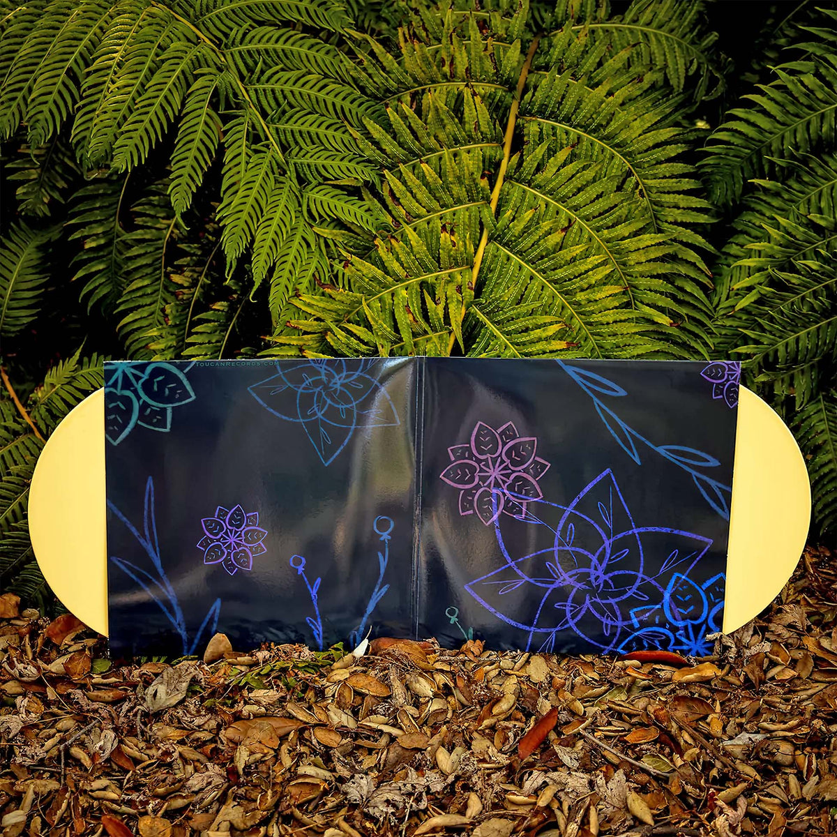 C418 Wanderstop gatefold packshot for the indie exclusive 2LP vinyl VGM soundtrack, Yellow Palm edition at ToucanRecords.com. Gatefold is open with discs visible. Photographed with ferns and dead oak eaves.