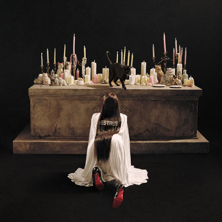 Tove Lo Estrus album cover for Ruby Red vinyl LP with gatefold jacket, printed inner sleeve, photo insert, and lyric insert. Cover features a black cat on an alter with cat figurines and lit candles. Tove Lo is in a crawling position while looking at the black cat.